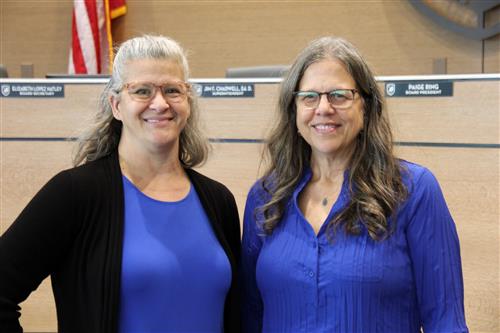 Two smiling women wearing purple tops